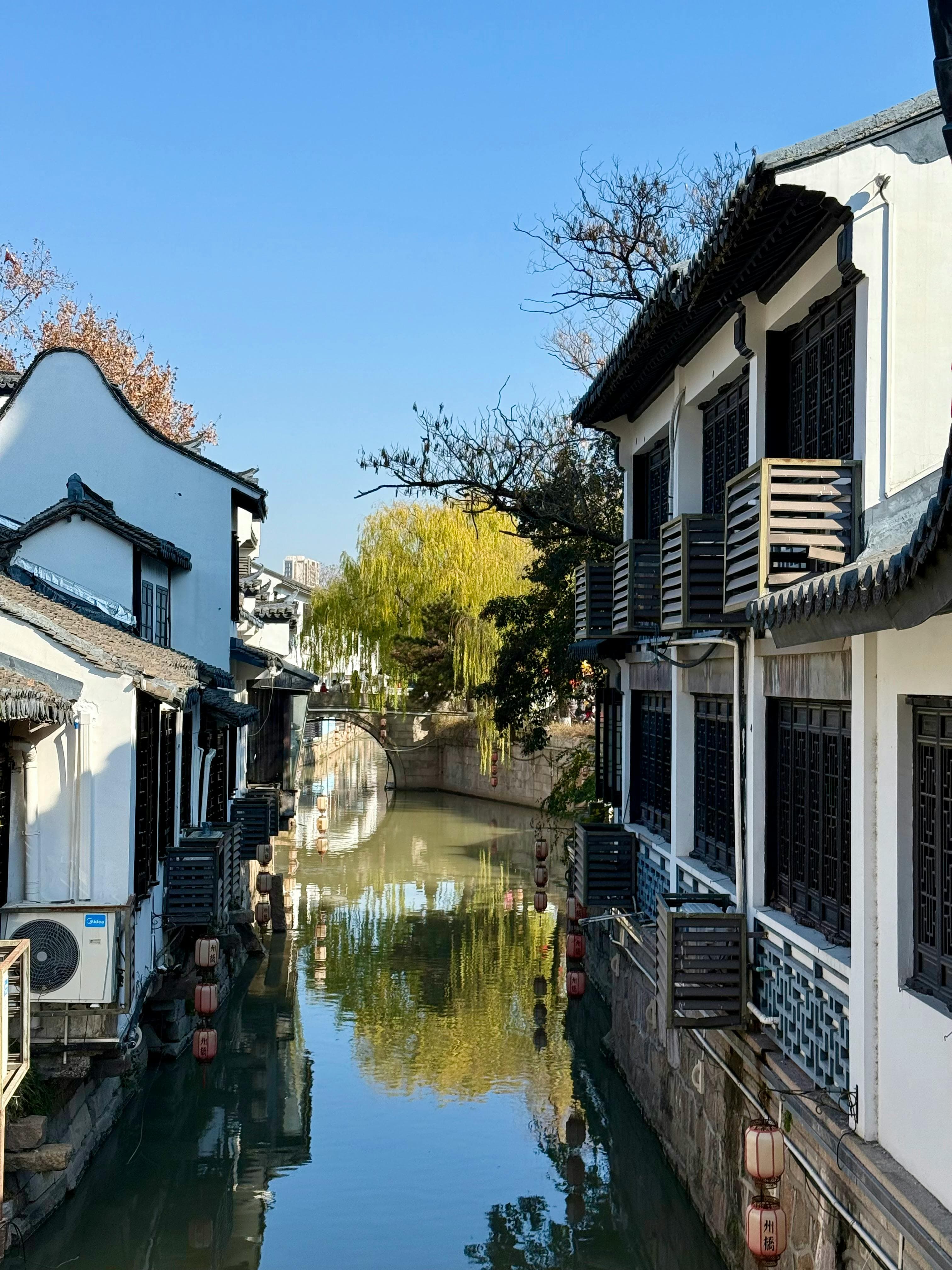 Classical Chinese garden in Suzhou with intricate rockeries, curved bridges over koi ponds, and traditional pavilions surrounded by bamboo groves