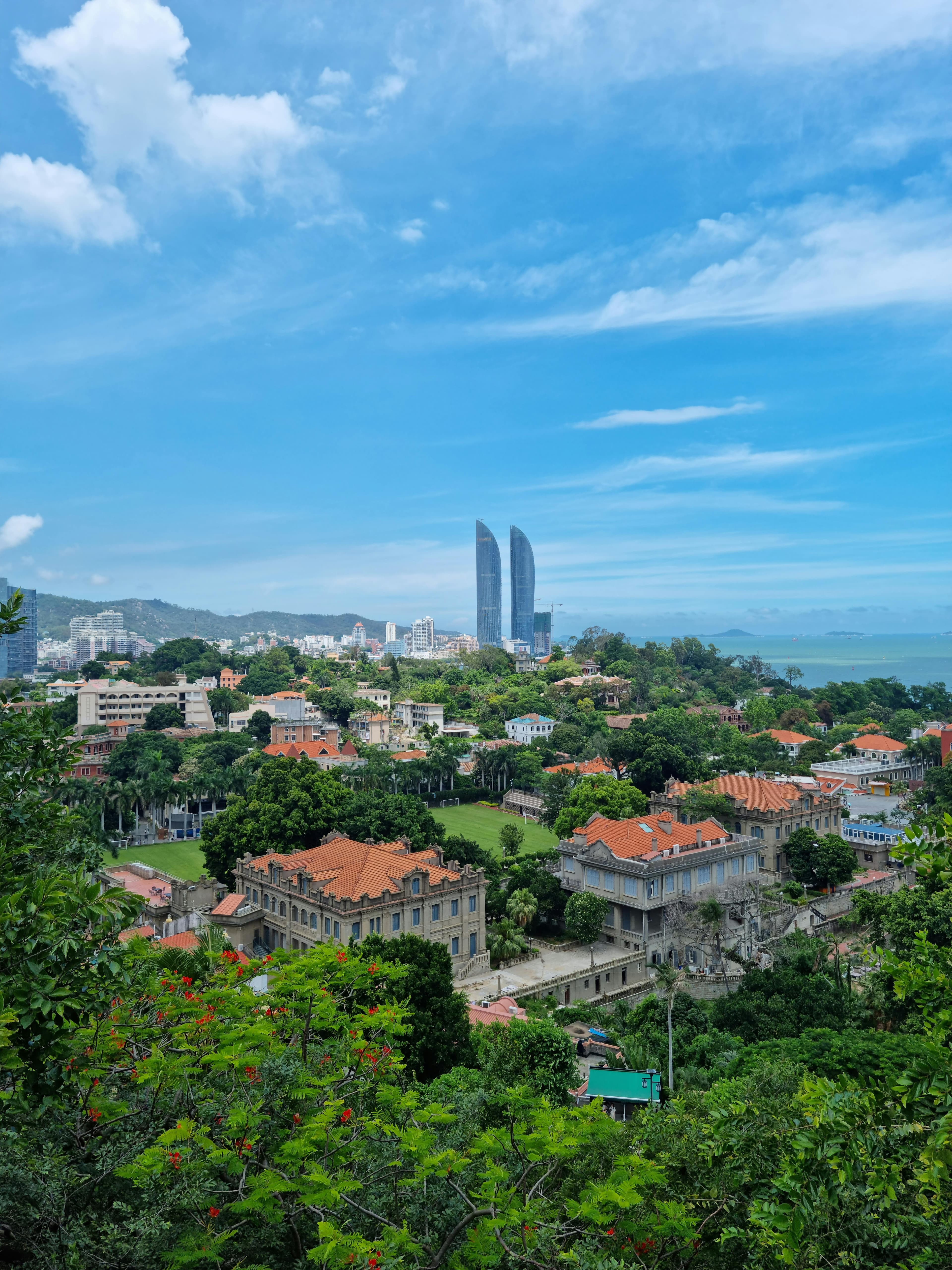 Colonial-era buildings on Gulangyu Island with European-style architecture, tree-lined streets, and the Xiamen skyline visible across the water